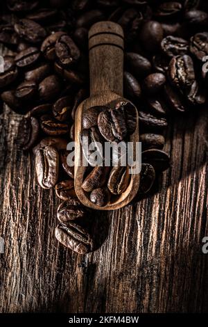 Grains de café frais dans une cuillère sur une planche en bois. Banque D'Images