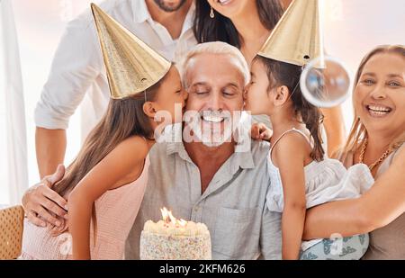 La famille, l'anniversaire et les filles embrassent le grand-père à la maison dans la célébration. Grande famille, gâteau et enfants embrassant grand-père avec grand-mère, mère et père Banque D'Images