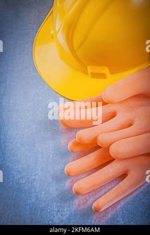 Gants isolants en caoutchouc pour la construction d'un casque sur fond métallique. Banque D'Images