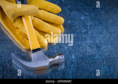 Gants de construction en cuir avec marteau à griffe sur fond métallique rayé copie espace image concept de bâtiment. Banque D'Images