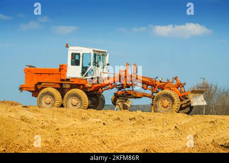 vieux tracteur de travail de route debout sur une pile de sable sur fond de ciel Banque D'Images