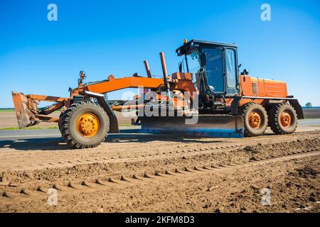 tracteur de chantier orange debout sur le bord de la route Banque D'Images