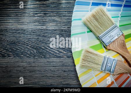 Les pinceaux colorent le ventilateur Pantone sur le panneau de bois. Banque D'Images