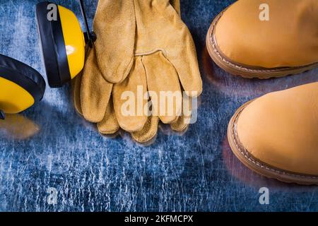 Bottes de sécurité gants en cuir et écouteurs anti-bruit sur surface métallique rayée concept de construction horizontale de l'image. Banque D'Images