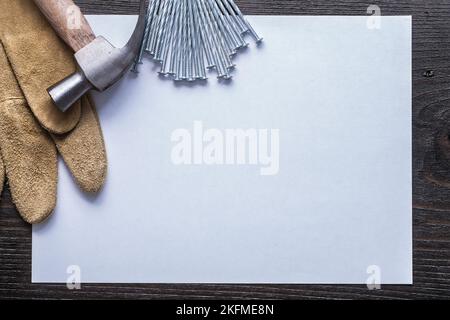 Feuille de papier clous en acier inoxydable marteau et gants de protection en cuir sur carton d'époque copyspace concept de construction. Banque D'Images