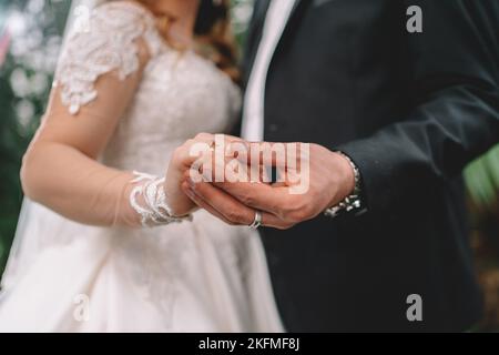 Un méconnaissable mariés l'échange des anneaux de mariage à l'église pendant la cérémonie du mariage chrétien Banque D'Images