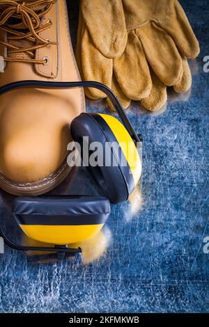 Bottes de travail gants de protection et écouteurs de réduction du bruit sur surface métallique rayée concept de conception de la vue du dessus. Banque D'Images