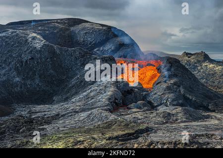 La lave coule d'un cratère volcanique. magma liquide rougeâtre chaud du volcan. Paysage volcanique sur la péninsule de Reykjanes en Islande. Magma sombre et refroidi Banque D'Images