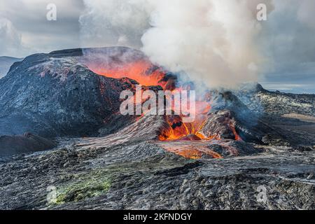 Vapeur intense et fumée sur un cratère volcanique. une lave rouge éclatante coule d'un cratère actif. Paysage en Islande sur la péninsule de Reykjanes. Nuages Banque D'Images