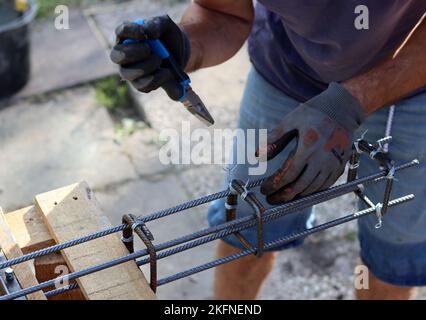 Acier de renfort de maintien manuel. Ouvrier de construction professionnel. Photo en gros plan des mains du constructeur dans des gants de protection. Banque D'Images