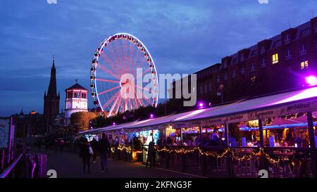 Promenade du Rhin à Düsseldorf pendant les fêtes avec l'extérieur du restaurant « Kasematten ». Grande roue et tour du château en arrière-plan. Banque D'Images