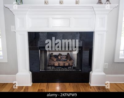 Un manteau blanc en bois orné avec cheminée à gaz dans une nouvelle maison de construction Banque D'Images