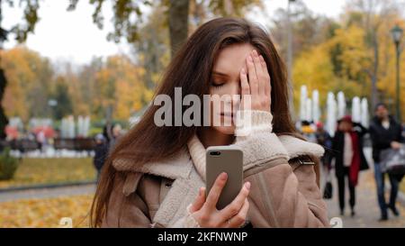 Portrait d'une fille triste frustrée femme étudiant caucasien chattant par téléphone mobile en plein air inquiet dame utiliser un smartphone en automne parc insatisfait Banque D'Images