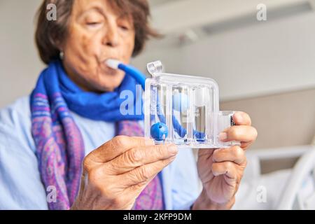 spiromètre pour exercices de respiration. femme sénior dans la chambre d'hôpital pratiquant avec le spiromètre Banque D'Images