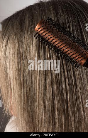 Une brosse est passée par de longs cheveux gris humains. Banque D'Images