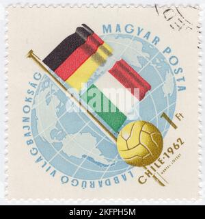 HONGRIE - 1962 21 mai : timbre-poste bleu de 1 ans et bister représentant le Globe, le ballon de football et les drapeaux d'Allemagne et d'Italie. Drapeaux aux couleurs nationales. Championnat du monde de football, Chili, 30 mai... 17 juin. Au total, 56 équipes ont participé aux phases de qualification de la coupe du monde de la FIFA 1962, se disputant un total de 16 places dans le tournoi final. Le Chili, en tant que pays hôte, et le Brésil, en tant que champions défendeurs, se sont automatiquement qualifiés, laissant 14 places ouvertes à la compétition Banque D'Images