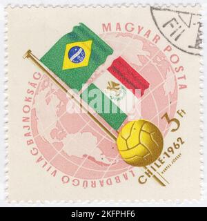 HONGRIE - 1962 21 mai : timbre-poste rose et bleu de 3 forints représentant le Globe, le ballon de football et les drapeaux de l'Argentine et de la Bulgarie. Drapeaux aux couleurs nationales. Championnat du monde de football, Chili, 30 mai... 17 juin. Au total, 56 équipes ont participé aux phases de qualification de la coupe du monde de la FIFA 1962, se disputant un total de 16 places dans le tournoi final. Le Chili, en tant que pays hôte, et le Brésil, en tant que champions défendeurs, se sont automatiquement qualifiés, laissant 14 places ouvertes à la compétition Banque D'Images