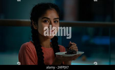 Une femme affamée d'Arabie mange un gâteau au chocolat dans un café en savourant une boulangerie fraîche avec un appétit en savourant un gâteau sucré dans un luxueux café-restaurant femelle Banque D'Images