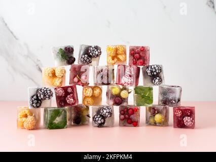 Cubes de glace congelés avec diverses baies, mûres et framboises, groseilles à maquereau et raisins de Corinthe, bleuets et menthe Banque D'Images