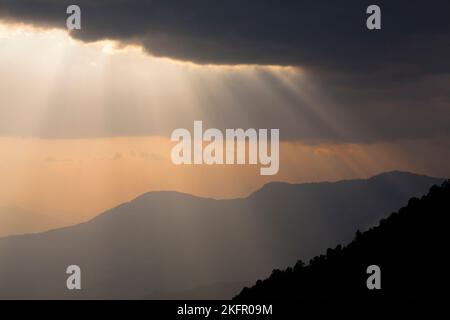 Poutres de soleil sur des contreforts de l'Himalaya silhouettés, au sud de la chaîne Annapurna. Népal. Banque D'Images