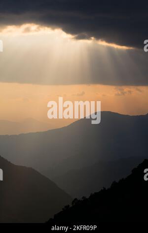 Poutres de soleil sur des contreforts de l'Himalaya silhouettés, au sud de la chaîne Annapurna. Népal. Banque D'Images