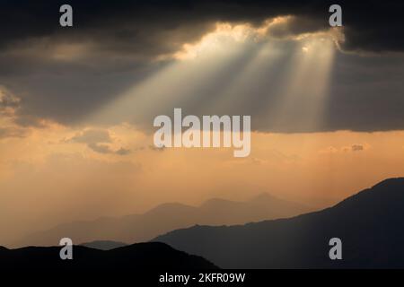 Poutres de soleil sur des contreforts de l'Himalaya silhouettés, au sud de la chaîne Annapurna. Népal. Banque D'Images