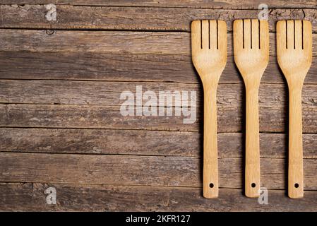Arrière-plan de lattes en bois rustiques et vieillies avec trois fourchettes en bois d'un côté. Banque D'Images