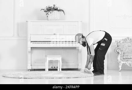 Employé tordu roulant un tapis. Homme avec tatouage sur le bras retirant tapis blanc de la chambre. Concept de rénovation Banque D'Images