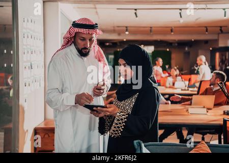 Photo portrait d'un homme d'affaires arabe dirigeant avec une hijab musulmane discutant de projets d'affaires tout en utilisant des tablettes et un smartphone dans un verre moderne Banque D'Images