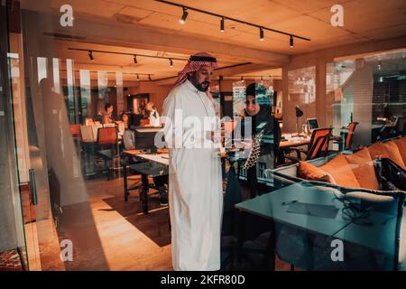 Photo portrait d'un homme d'affaires arabe dirigeant avec une hijab musulmane discutant de projets d'affaires tout en utilisant des tablettes et un smartphone dans un verre moderne Banque D'Images