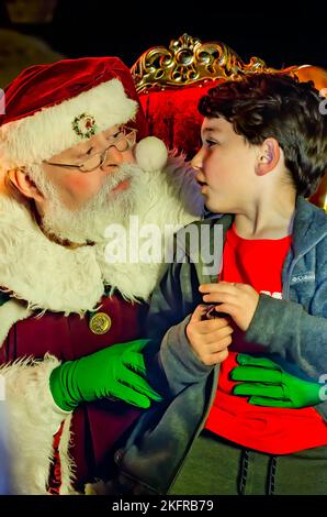 Un petit garçon est assis sur les genoux du Père Noël pendant l’éclairage des arbres de Noël de la ville au parc Mardi gras, le 18 novembre 2022, à Mobile, Alabama. Banque D'Images