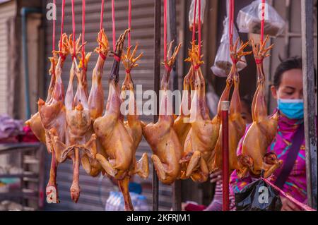 Une femme cambodgienne, portant un masque facial protecteur, vend des poulets entiers et crus pendant la pandémie COVID - 19. Phnom Penh, Cambodge. © Kraig Lieb Banque D'Images