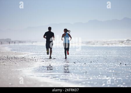 En plein air. Vue arrière d'un couple en train de courir ensemble sur la plage. Banque D'Images