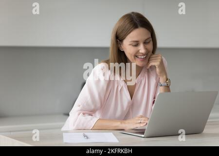 Jolie femme assis à une table dans la cuisine avec ordinateur portable Banque D'Images