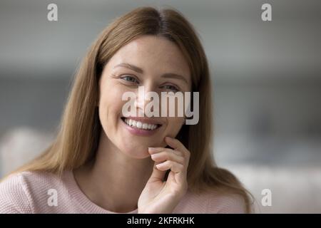 Jolie femme est assise à l'intérieur sourire en regardant de côté, portrait de gros plan Banque D'Images