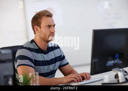 HES un individu orienté tâche. Un jeune homme concepteur travaillant à son ordinateur. Banque D'Images