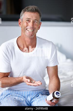 Cela me donne un coup de pouce quotidien. Un homme mûr assis sur un lit avec son médicament. Banque D'Images