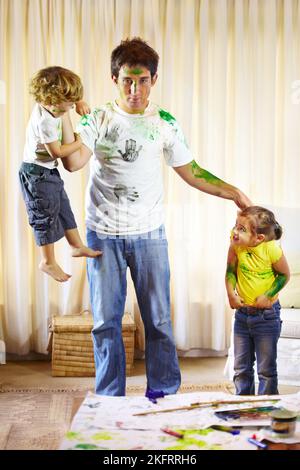 Je pense qu'ils ont besoin d'un délai d'attente. Le jeune père démissionna, tenant ses enfants qui ont peint tout autour de lui. Banque D'Images