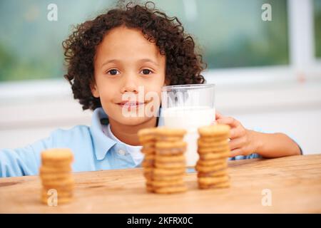 MMM, tellement de cookies juste pour moi. Un jeune garçon mignon saisissant un cookie du pot à biscuits. Banque D'Images