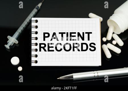 Concept de médecine et de soins de santé. Sur la surface noire se trouvent des pilules, une seringue et un carnet avec l'inscription - dossiers de patient Banque D'Images