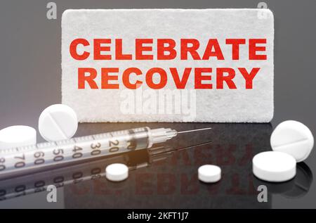 Médecine et concept de santé. Sur une surface réfléchissante noire, des pilules, une seringue et un signe avec l'inscription - Celebrate Recovery Banque D'Images