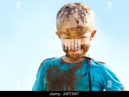 Un super-héros boueux. Un petit garçon habillé comme un super-héros et couvert de boue. Banque D'Images