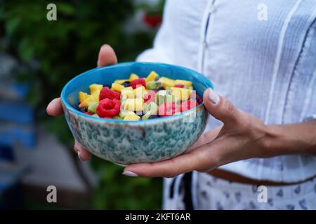 Attention douce de la femme anonyme montrant un bol de salade de fruits sains le jour de l'été dans la cour Banque D'Images