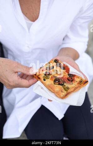 De dessus de la femelle anonyme en chemise blanche tenant un morceau de pizza savoureuse avec la tomate et le fromage et les olives coupées Banque D'Images