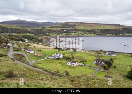 D'en haut vue panoramique sur un petit village situé parmi les collines verdoyantes près du lac calme le jour couvert Banque D'Images