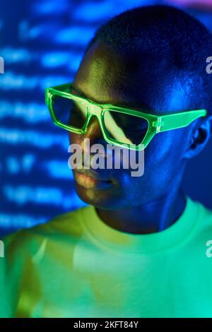 Crop jeune Afro-américain mâle dans des lunettes de vue passant du temps dans la boîte de nuit avec un éclairage lumineux Banque D'Images