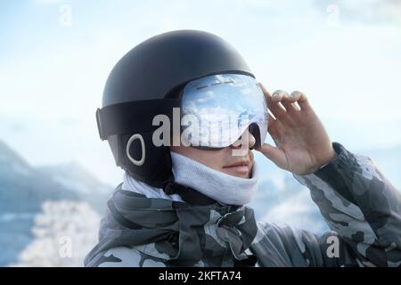 Gros plan sur les lunettes de ski d'un homme avec le reflet des montagnes enneigées.Une chaîne de montagnes reflétée dans le masque de ski.Portrait de l'homme au ski r Banque D'Images