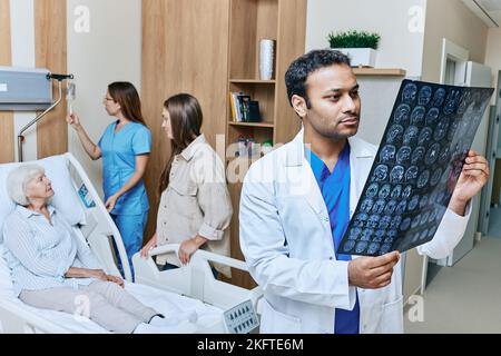 Médecin neurologue regardant les images IRM de la tête du patient senior qui est couché dans le service de neurologie de l'hôpital. Neurologie et IRM du cerveau Banque D'Images