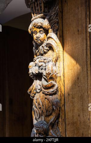 Illuminé par un rayon de soleil, sculpture d'un chérubin dans le bois de la porte principale de l'église de la Madeleine à Bruxelles. Banque D'Images