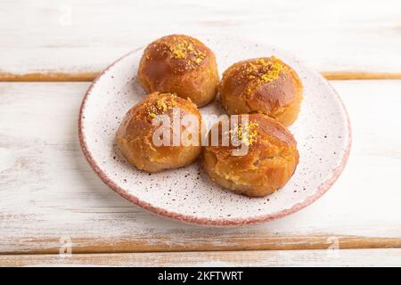 Dessert turc traditionnel fait maison, sekerpares aux amandes et au miel sur fond de bois blanc. Vue latérale, gros plan. Banque D'Images